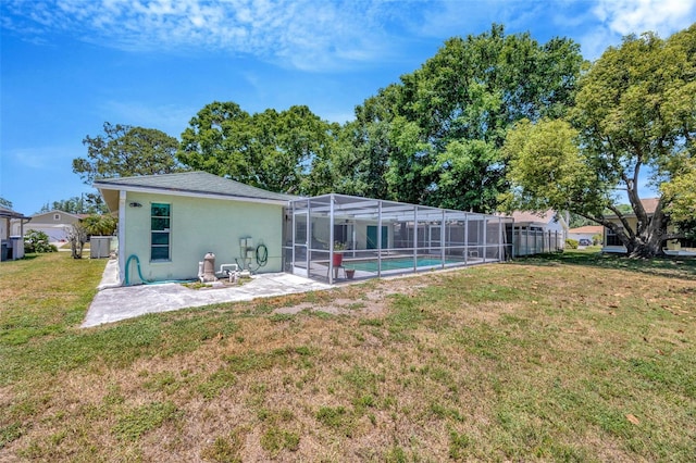 back of house with an outdoor pool, stucco siding, a patio area, a lanai, and a yard