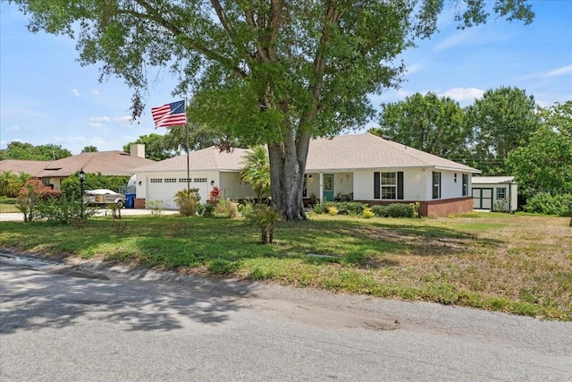 ranch-style home with driveway, a storage shed, a front yard, and a garage