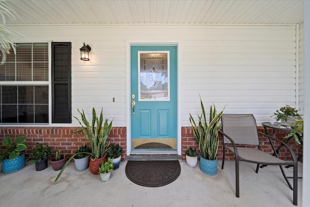 view of exterior entry featuring a porch and brick siding