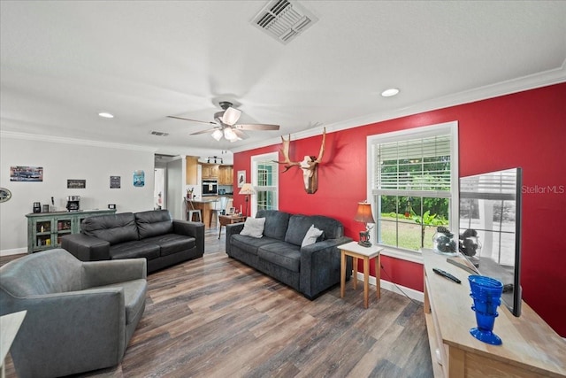 living room with crown molding, visible vents, ceiling fan, and wood finished floors