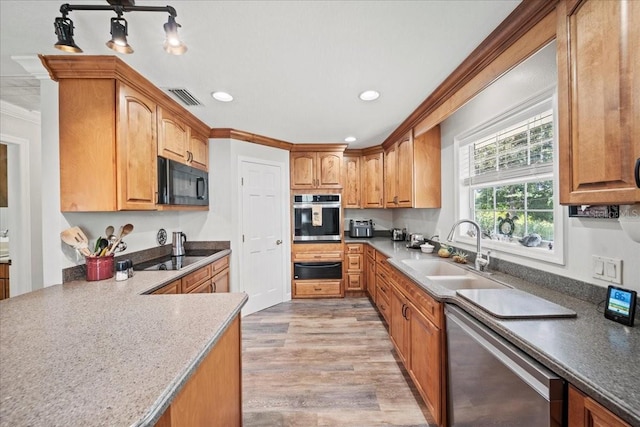 kitchen featuring light wood finished floors, a sink, a warming drawer, black appliances, and visible vents
