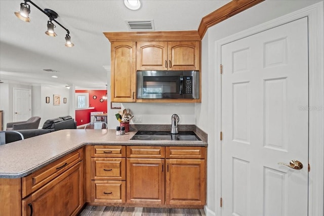 kitchen with a sink, brown cabinets, visible vents, a peninsula, and open floor plan