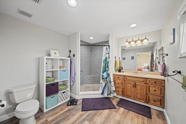 full bathroom with toilet, vanity, a shower stall, and wood finished floors