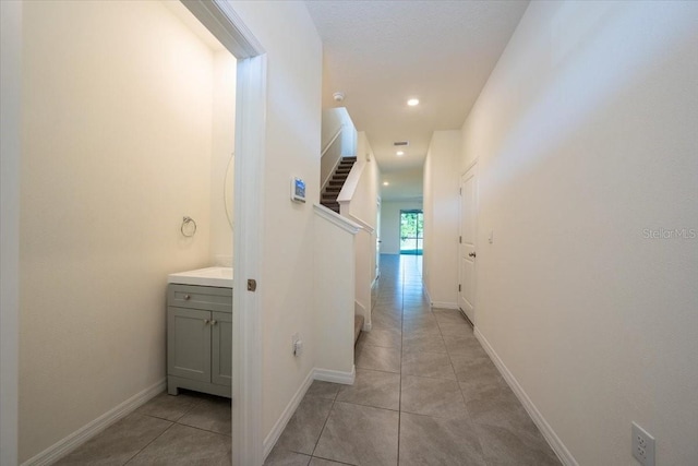 corridor with recessed lighting, baseboards, and light tile patterned flooring