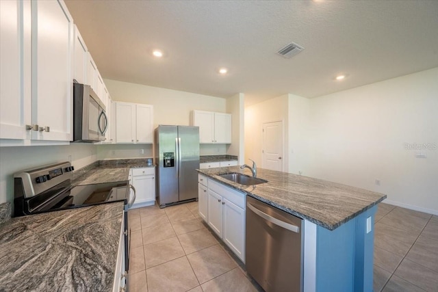 kitchen with visible vents, a sink, dark stone countertops, stainless steel appliances, and white cabinetry
