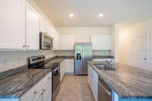 kitchen featuring a sink, a kitchen island with sink, stainless steel appliances, and white cabinetry
