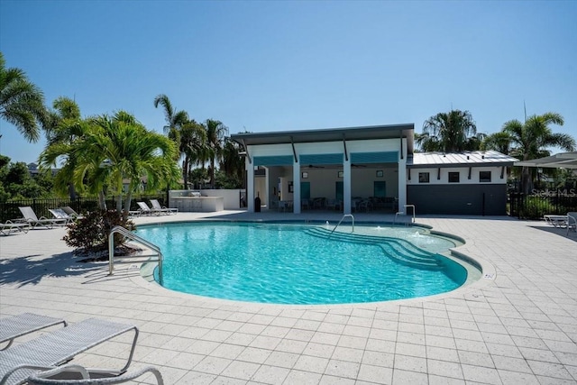 community pool with a patio area and fence
