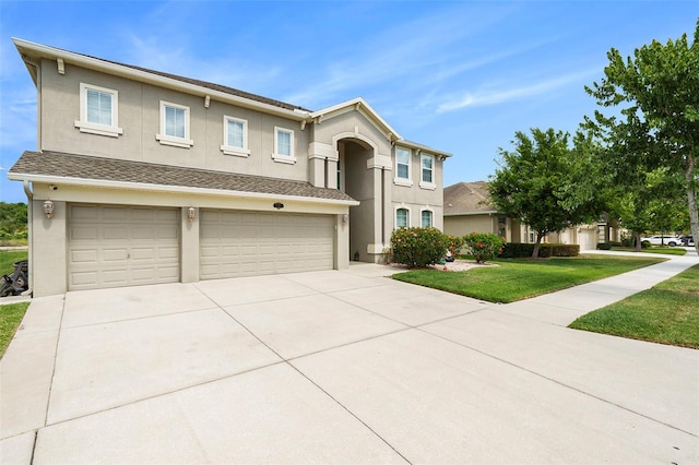 view of front facade with an attached garage, stucco siding, driveway, and a front yard