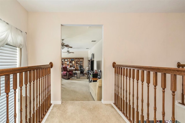 hall with carpet floors, baseboards, an upstairs landing, and visible vents