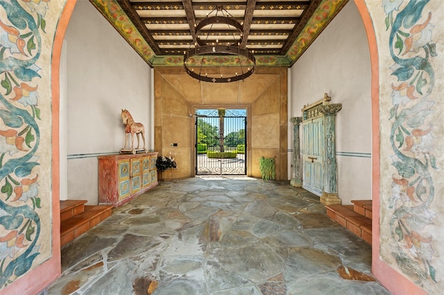hallway featuring stone flooring, coffered ceiling, arched walkways, and beam ceiling