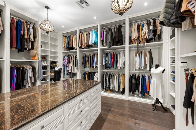 walk in closet featuring an inviting chandelier, dark wood-style floors, and visible vents