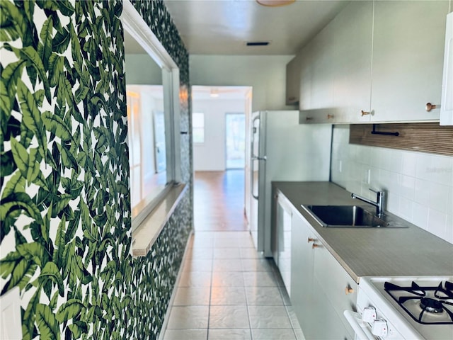 5660 80th St N Unit C101, Saint Petersburg, FL 33709 - kitchen featuring dark countertops, white gas stove, white cabinets, a sink, and backsplash