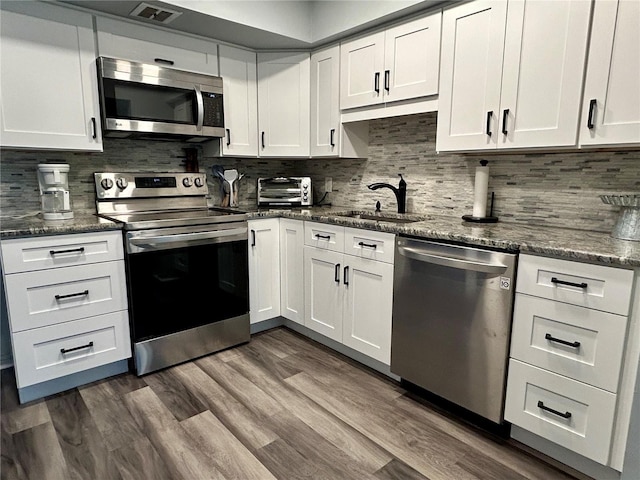 2020 World Parkway Blvd Unit 14, Clearwater, FL 33763 - kitchen featuring decorative backsplash, white cabinets, a sink, appliances with stainless steel finishes, and visible vents