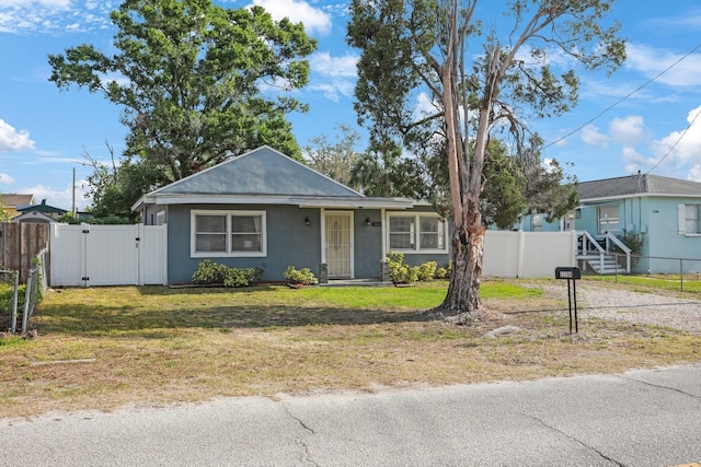 view of front of house with stucco siding, fence, a gate, and a front yard