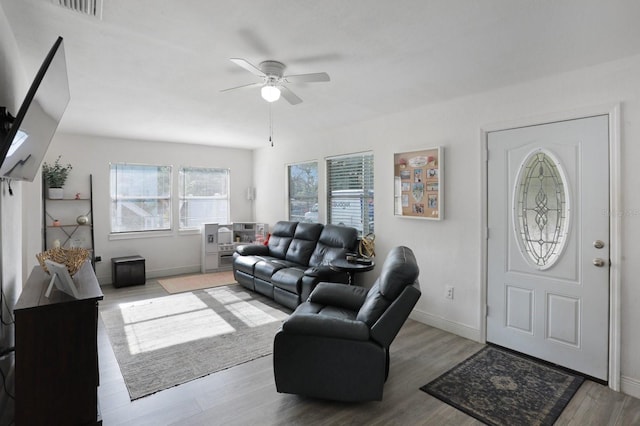 living area with wood finished floors, visible vents, a ceiling fan, and baseboards