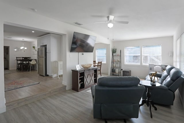 living area with baseboards, visible vents, ceiling fan with notable chandelier, and light wood-style floors