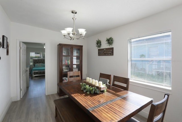 dining room featuring light wood finished floors, a chandelier, and baseboards