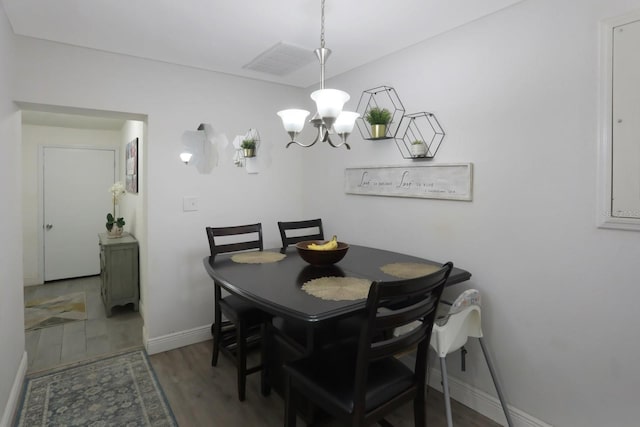 dining room featuring visible vents, wood finished floors, a notable chandelier, and baseboards