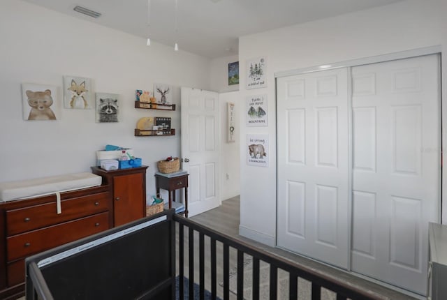 bedroom with a closet, visible vents, and wood finished floors