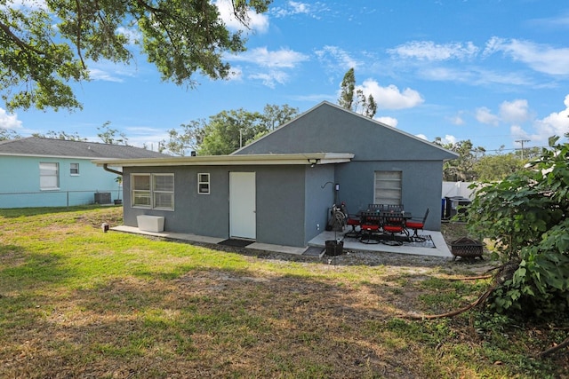 back of house with an outdoor fire pit, stucco siding, a yard, fence, and a patio
