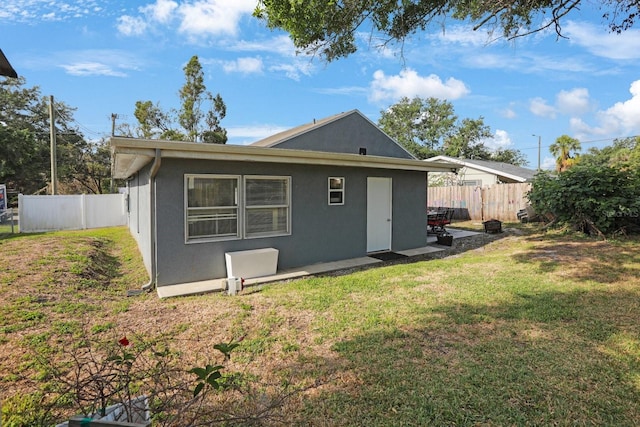 back of property featuring a lawn, stucco siding, a fenced backyard, and a patio area