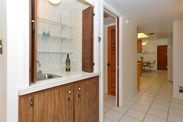 bar featuring light tile patterned floors, ceiling fan, freestanding refrigerator, and visible vents
