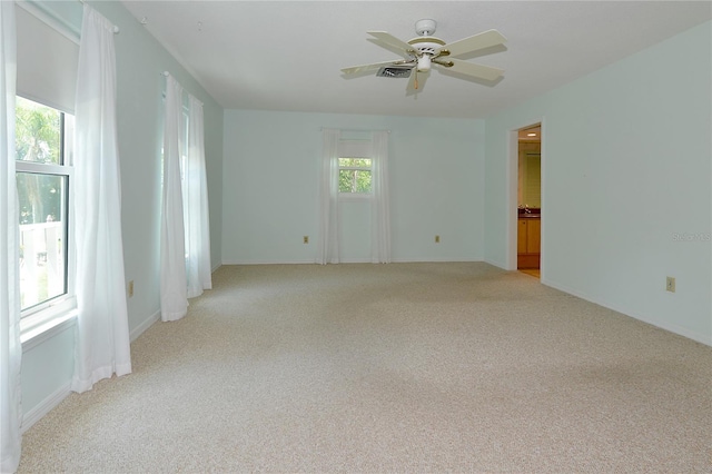 empty room featuring light colored carpet, baseboards, ceiling fan, and visible vents
