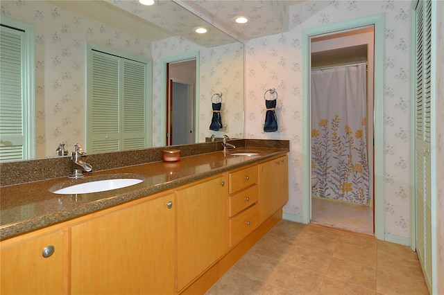 full bath with double vanity, a sink, and wallpapered walls