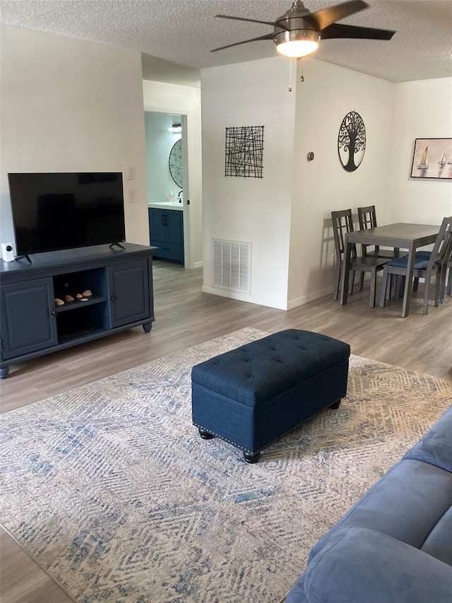 7951 58th Ave N Unit 308, Saint Petersburg, FL 33709 - living area with light wood-style flooring, a ceiling fan, a textured ceiling, and baseboards
