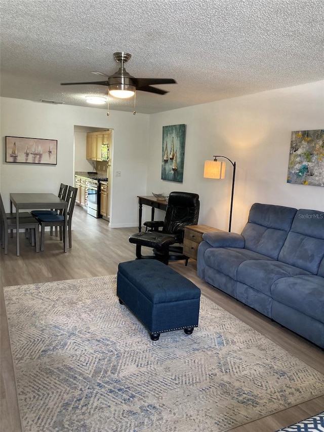 7951 58th Ave N Unit 308, Saint Petersburg, FL 33709 - living room featuring light wood-type flooring, a ceiling fan, a textured ceiling, and baseboards