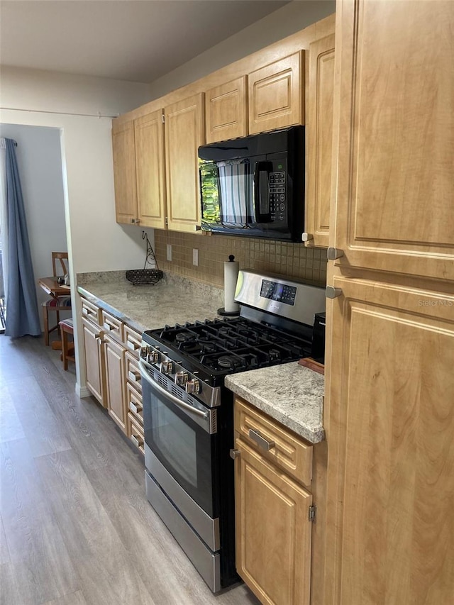 7951 58th Ave N Unit 308, Saint Petersburg, FL 33709 - kitchen with black microwave, stainless steel gas range, light wood-style flooring, tasteful backsplash, and light brown cabinets
