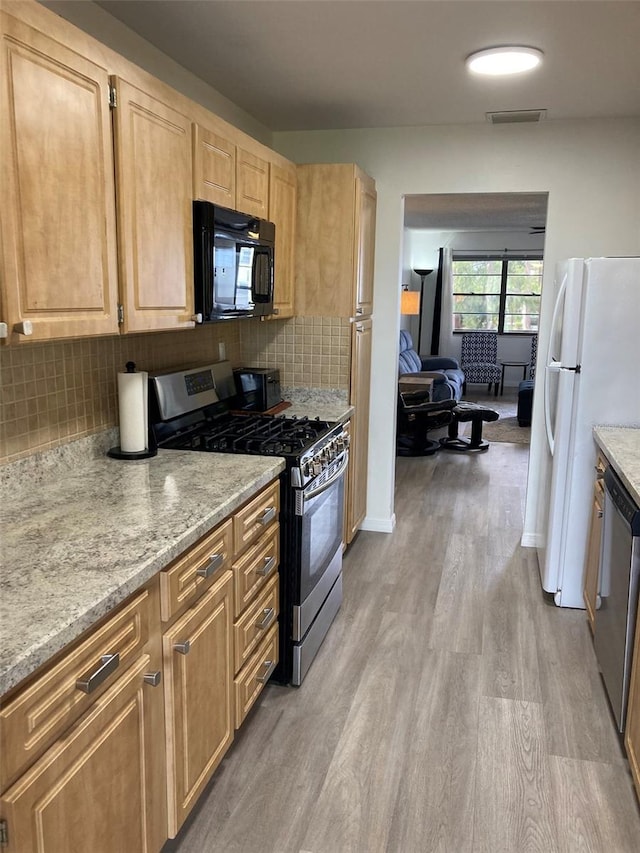 7951 58th Ave N Unit 308, Saint Petersburg, FL 33709 - kitchen featuring stainless steel appliances, light wood-style flooring, backsplash, light brown cabinets, and light stone countertops