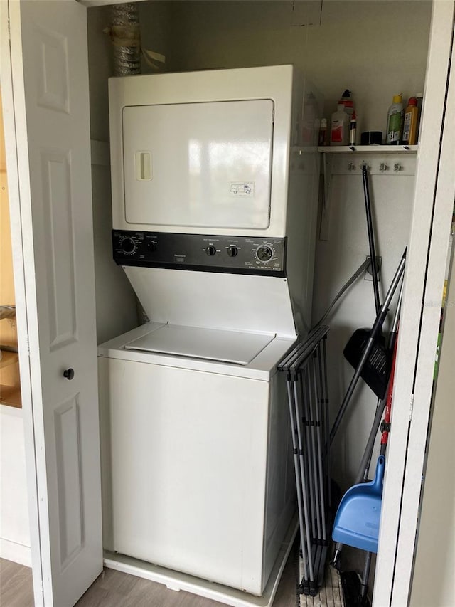 7951 58th Ave N Unit 308, Saint Petersburg, FL 33709 - clothes washing area featuring stacked washing machine and dryer and wood finished floors