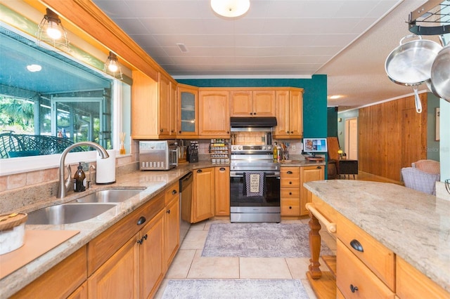 kitchen featuring light stone counters, a sink, stainless steel appliances, under cabinet range hood, and glass insert cabinets