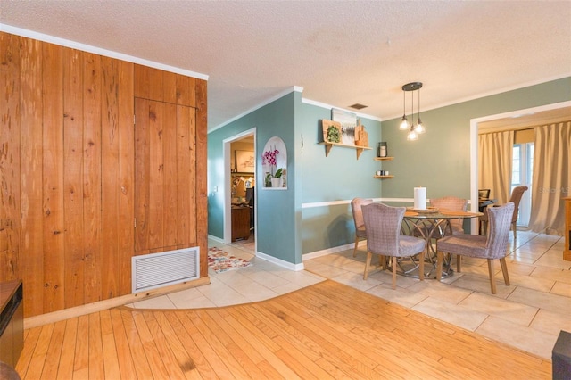 tiled dining room with visible vents, a textured ceiling, and crown molding