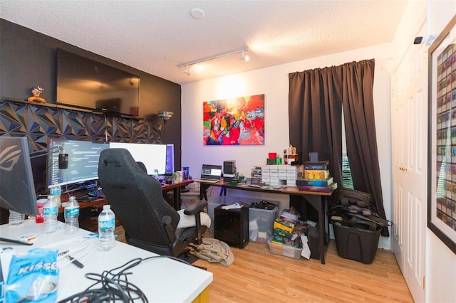 home office featuring track lighting, a textured ceiling, and wood finished floors