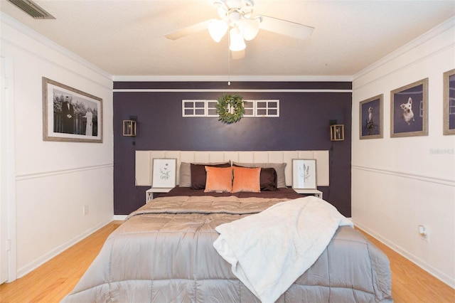 bedroom with ornamental molding, wood finished floors, and visible vents
