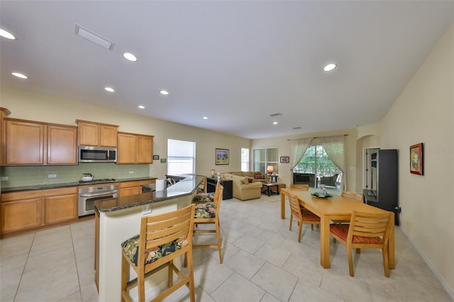 3315 Granite Ridge Loop, Land O Lakes, FL 34638 - kitchen with stainless steel appliances, tasteful backsplash, a breakfast bar, arched walkways, and light tile patterned floors