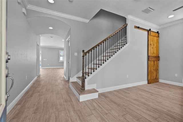 entrance foyer with arched walkways, baseboards, light wood-type flooring, visible vents, and ornamental molding