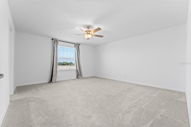 carpeted spare room with baseboards and a ceiling fan