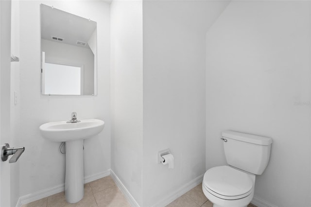 half bath featuring tile patterned floors, toilet, and baseboards