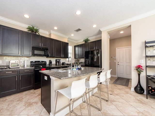 311 Vista Cruiser Ln, Oldsmar, FL 34677 - kitchen featuring black appliances, a sink, a kitchen breakfast bar, dark stone counters, and an island with sink
