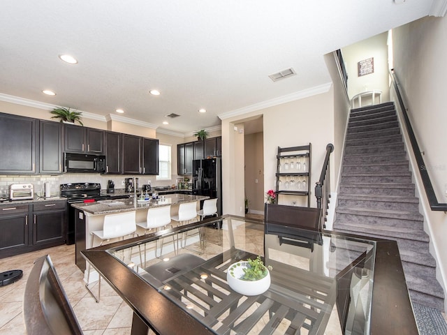 311 Vista Cruiser Ln, Oldsmar, FL 34677 - kitchen featuring black appliances, light stone countertops, recessed lighting, crown molding, and a center island with sink