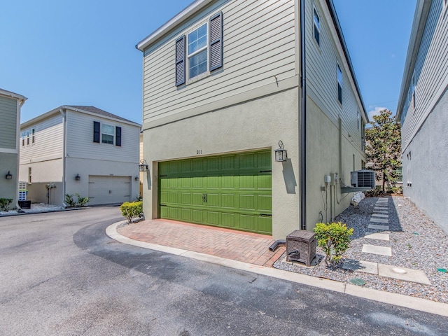311 Vista Cruiser Ln, Oldsmar, FL 34677 - view of side of property with an attached garage, stucco siding, cooling unit, and decorative driveway