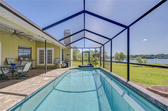 pool featuring a patio, a water view, glass enclosure, and a yard