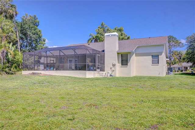 rear view of property featuring glass enclosure, a chimney, a yard, and stucco siding