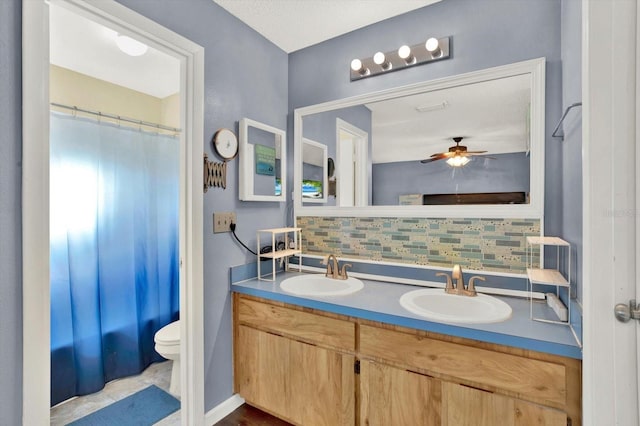 bathroom featuring a sink, tasteful backsplash, toilet, and double vanity