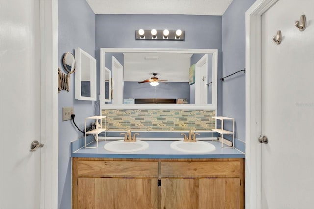 full bath with backsplash, a ceiling fan, a sink, and double vanity