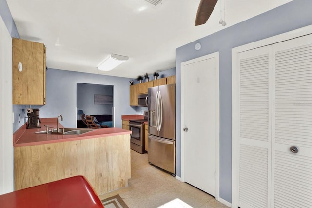 kitchen featuring a sink, appliances with stainless steel finishes, a peninsula, and light floors