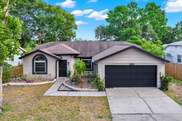 single story home with brick siding, fence, a front lawn, concrete driveway, and an attached garage
